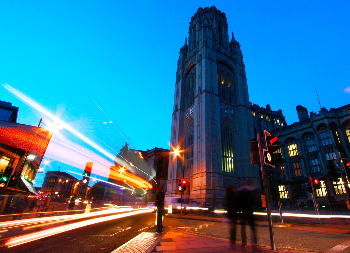 The University of Bristol Wills Memorial Building tower at night, with flashes of lights from traffic passing by.